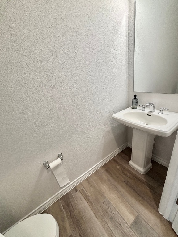 7606 Elk Grove Path Austin, TX 78653 - Photo 14 of 40 Half bathroom featuring light wood-type flooring and a textured wall