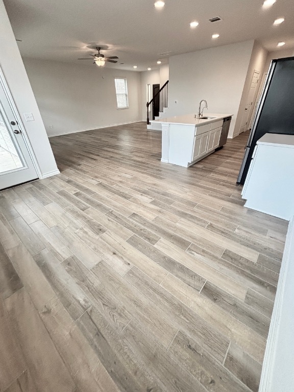 7606 Elk Grove Path Austin, TX 78653 - Photo 40 of 40 Kitchen with open floor plan, recessed lighting, freestanding refrigerator, a center island with sink, and light wood-style flooring