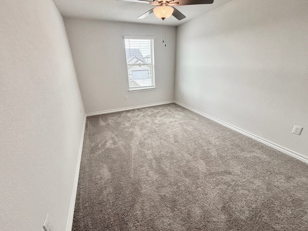 7606 Elk Grove Path Austin, TX 78653 - Photo 25 of 40 Carpeted spare room featuring a textured wall and a ceiling fan