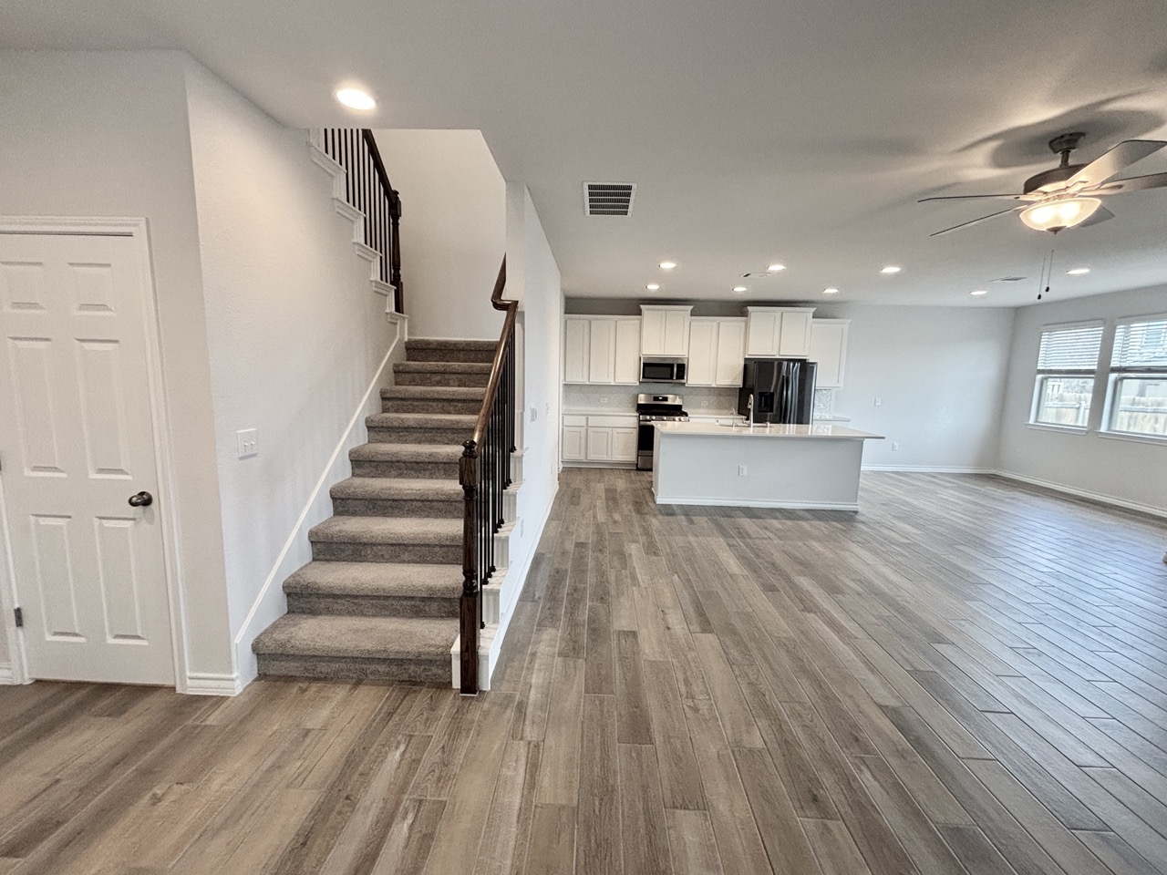 7606 Elk Grove Path Austin, TX 78754 - Photo 36 of 40 Kitchen featuring open floor plan, recessed lighting, white cabinetry, light wood finished floors, and a kitchen island with sink