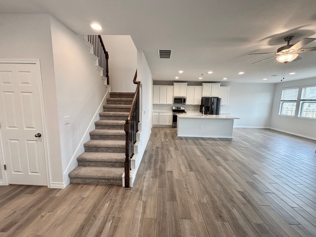 7606 Elk Grove Path Austin, TX 78653 - Photo 36 of 40 Kitchen featuring open floor plan, recessed lighting, white cabinetry, light wood finished floors, and a kitchen island with sink