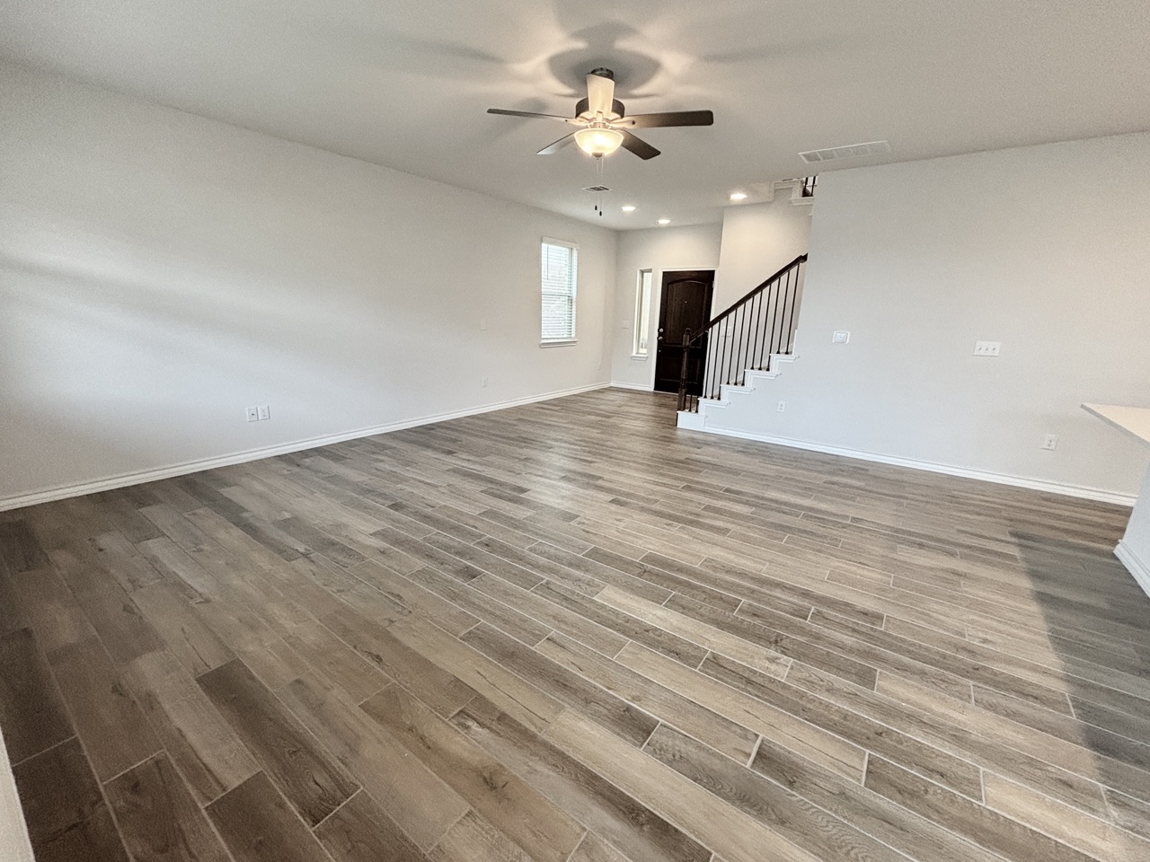 7606 Elk Grove Path Austin, TX 78754 - Photo 6 of 40 Unfurnished living room with light wood-style floors, ceiling fan, recessed lighting, and stairway