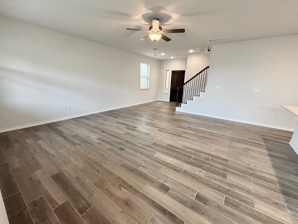 7606 Elk Grove Path Austin, TX 78653 - Photo 6 of 40 Unfurnished living room with light wood-style floors, ceiling fan, recessed lighting, and stairway