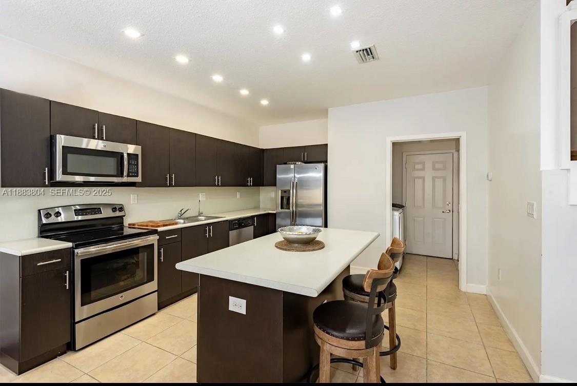 22509 Southwest 102nd Avenue Miami, FL 33190 - Photo 20 of 39 a kitchen with stainless steel appliances granite countertop a stove top oven a sink dishwasher a dining table and chairs with wooden floor