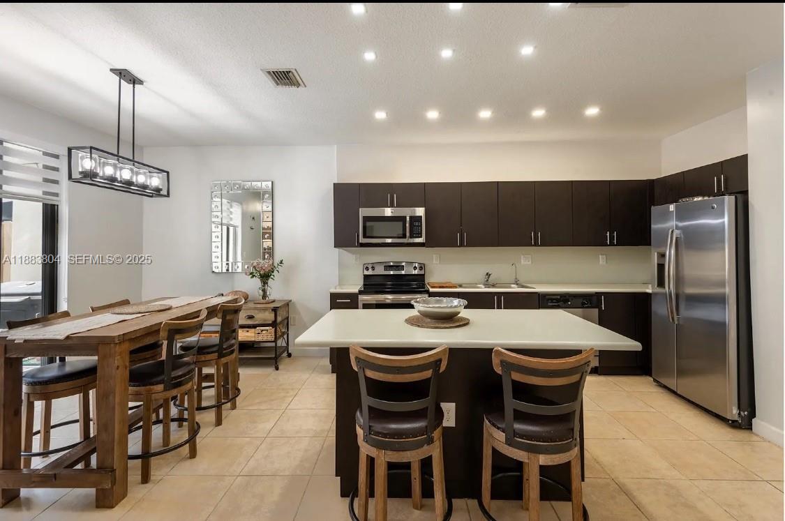 22509 Southwest 102nd Avenue Miami, FL 33190 - Photo 21 of 39 a kitchen with stainless steel appliances a table chairs refrigerator and microwave