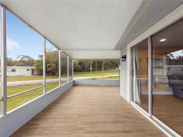 a view of an empty room with wooden floor and a floor to ceiling window
