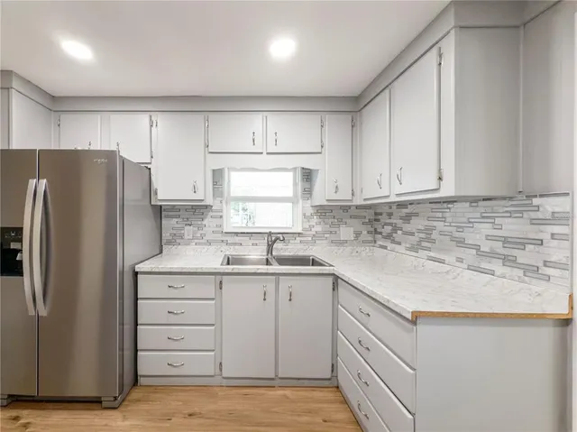 a kitchen with white cabinets sink and refrigerator