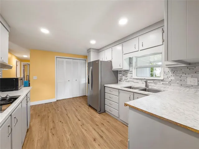 a kitchen with a sink a refrigerator and a stove top oven