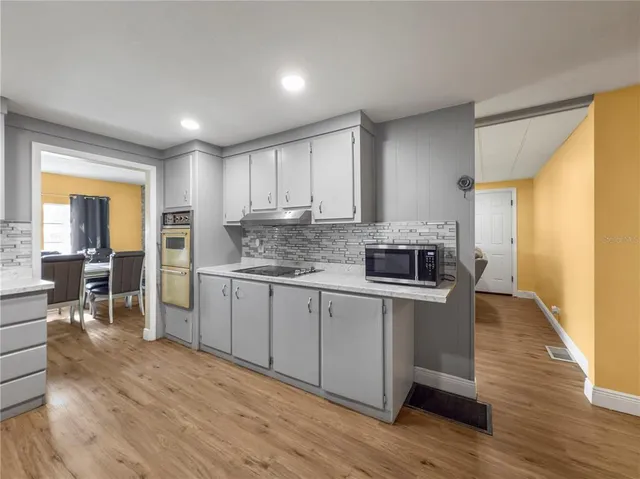 a kitchen with granite countertop a stove top oven a sink dishwasher a dining table and chairs with wooden floor