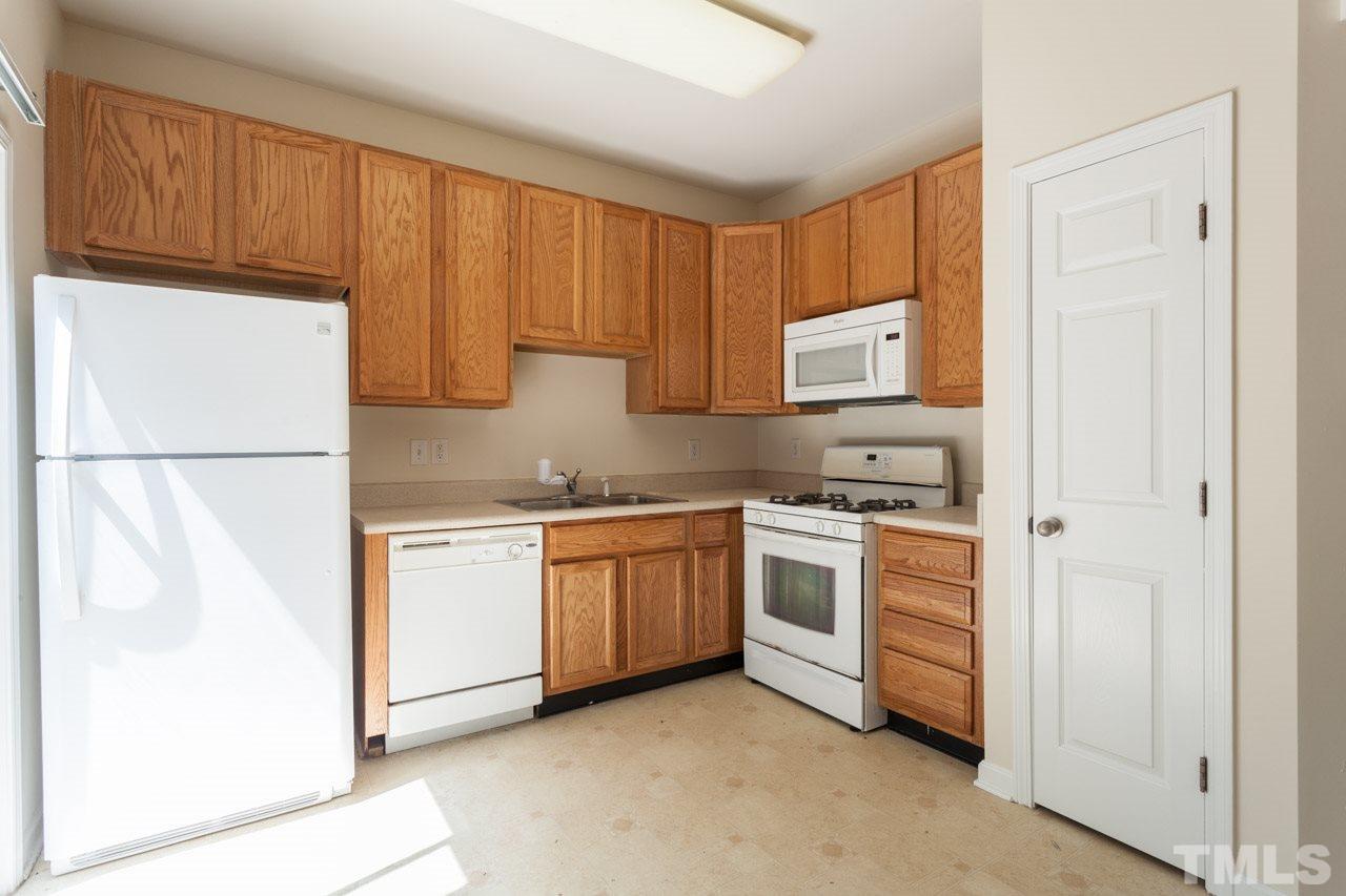 8631 Neuse Club Lane, Unit 100 Raleigh, NC 27616 - Photo 12 of 25 a kitchen with stainless steel appliances granite countertop a refrigerator sink and stove