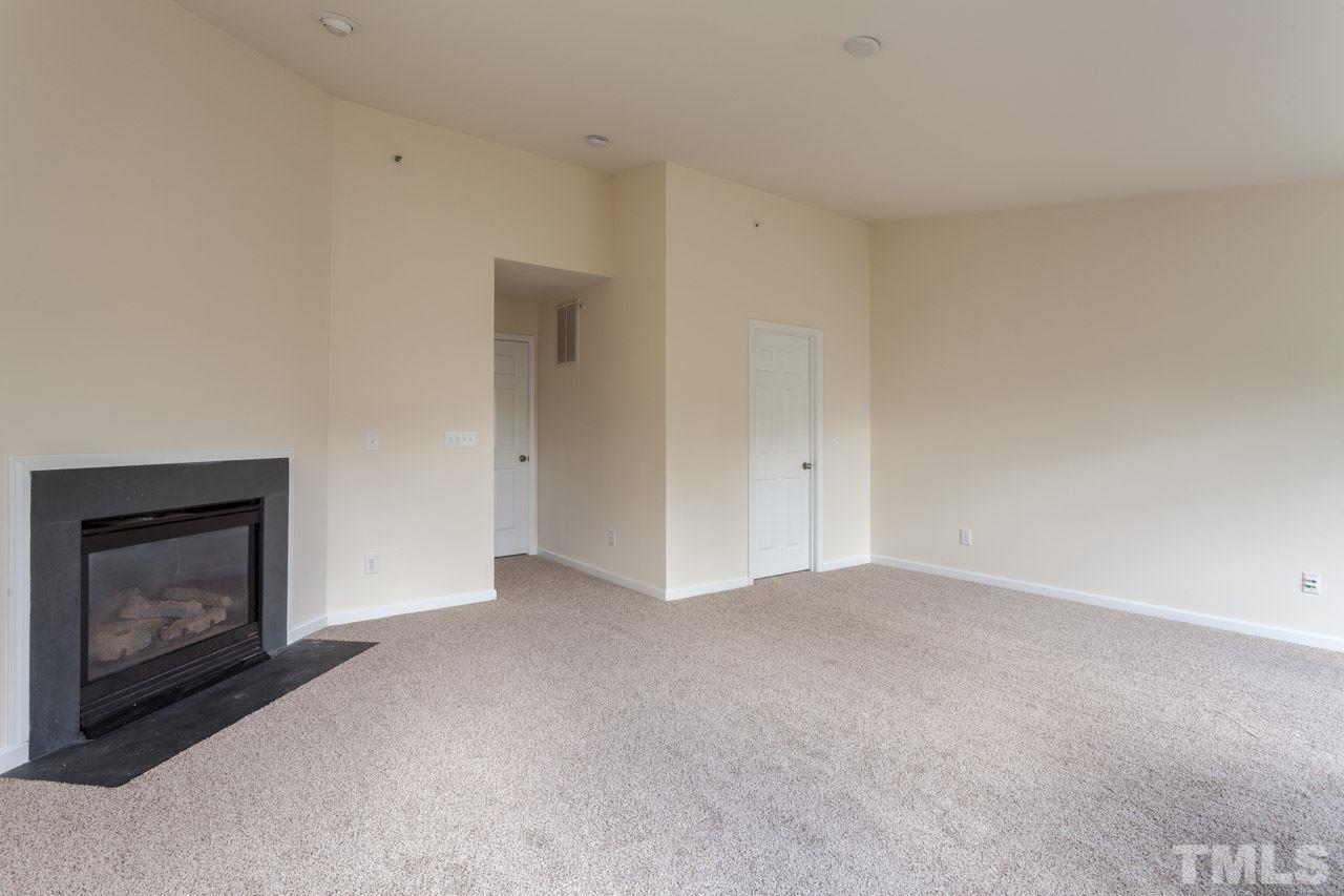 8631 Neuse Club Lane, Unit 100 Raleigh, NC 27616 - Photo 8 of 25 a view of an empty room with a fireplace and a window