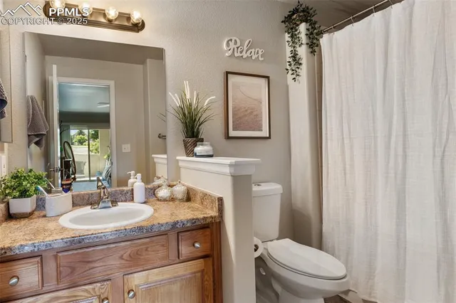 a bathroom with a granite countertop sink a toilet and a mirror