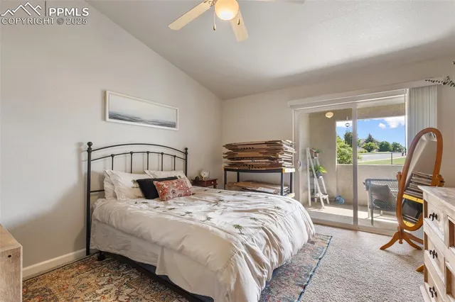 a bedroom with a bed a large window and a potted plant on the dresser