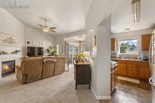 a view of living room kitchen with stainless steel appliances kitchen island granite countertop furniture and a fireplace