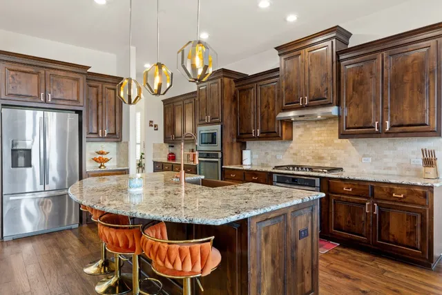 a kitchen with stainless steel appliances granite countertop a sink a stove and a wooden floors
