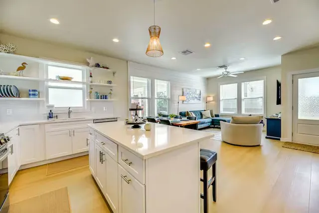 a large white kitchen with a large window and stainless steel appliances