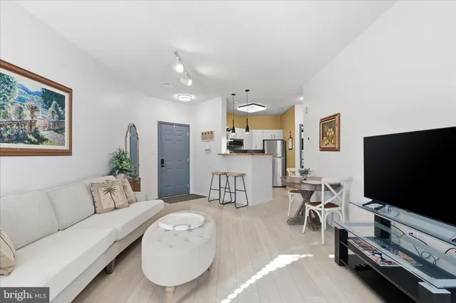 a kitchen with stainless steel appliances kitchen island granite countertop a refrigerator a stove top oven a dining table and chairs with wooden floor