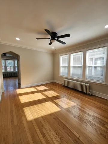 a view of empty room with wooden floor and fan
