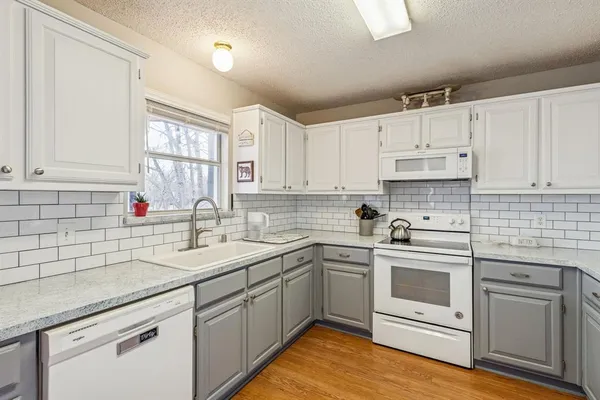 a kitchen with white cabinets sink and appliances