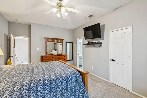 a bedroom with a bed and a flat tv screen on dresser