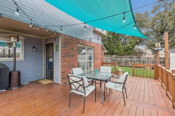 a view of a patio with table and chairs with wooden floor and fence