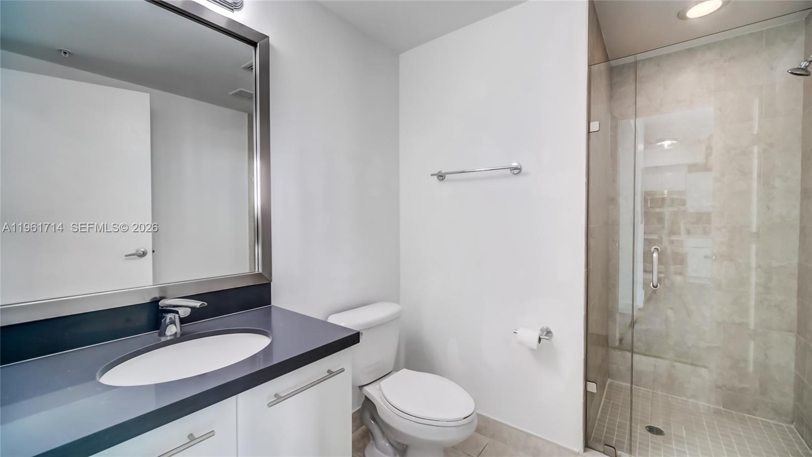 90 Southwest 3rd Street, Unit TH706 Miami, FL 33130 - Photo 6 of 37 a bathroom with a granite countertop sink toilet a mirror and shower