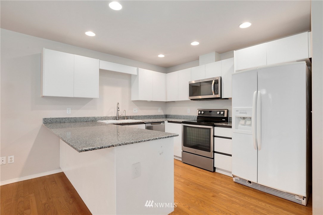 17539 110 Lane Southeast, Unit 20 Renton, WA 98055 - Photo 3 of 25 a kitchen with stainless steel appliances granite countertop a stove a sink and a refrigerator with wooden floor