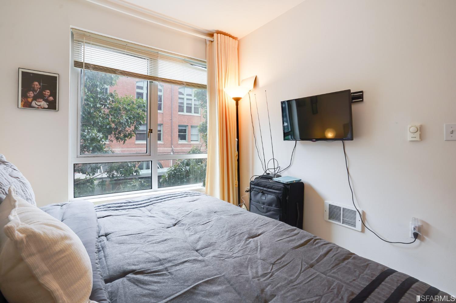 888 7th Street, Unit 120 San Francisco, CA 94107 - Photo 5 of 20 a bedroom with a bed and a flat tv screen next to a window