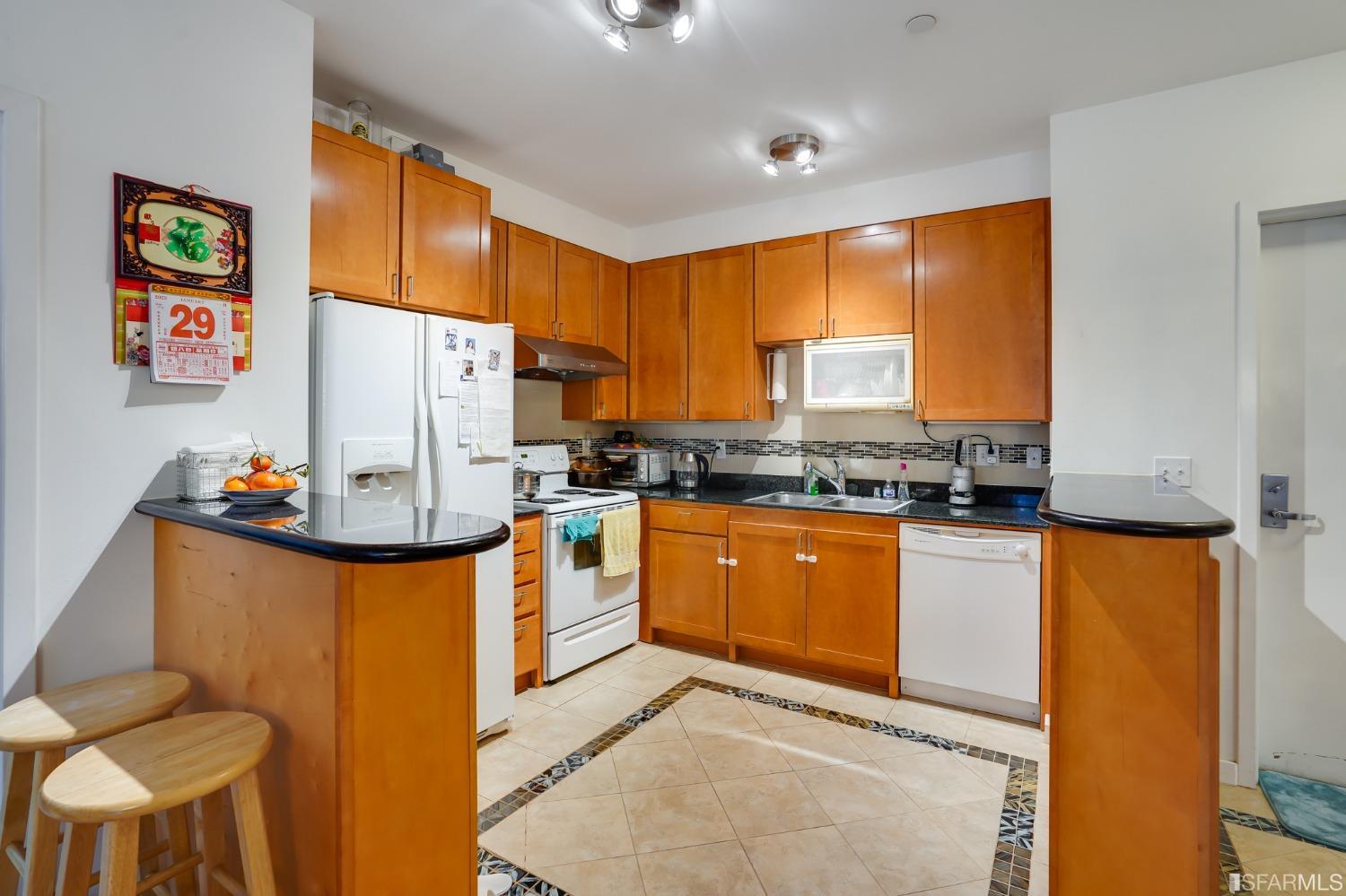 888 7th Street, Unit 120 San Francisco, CA 94107 - Photo 9 of 20 a kitchen with granite countertop a refrigerator a stove a sink a dining table and chairs