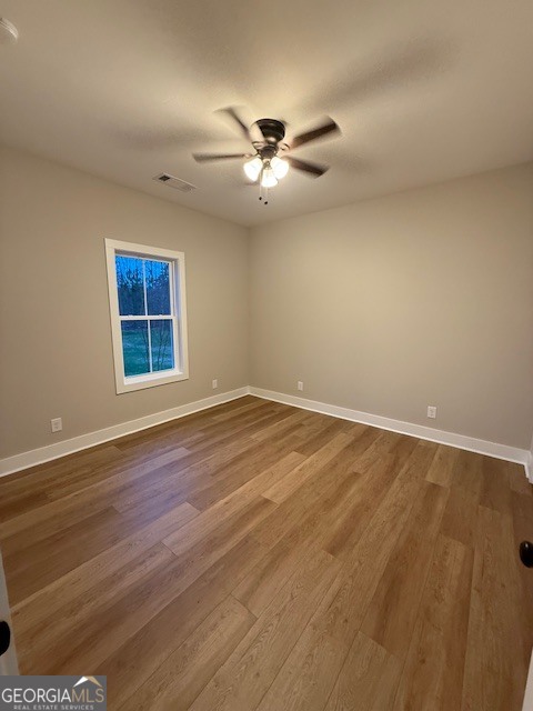 603 Silver Dollar Road Barnesville, GA 30204 - Photo 30 of 33 an empty room with wooden floor ceiling fan and windows