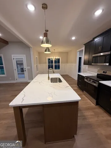 a large kitchen with kitchen island a stove a sink a counter space and cabinets