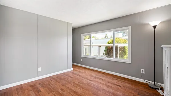 a view of an empty room with wooden floor and a window