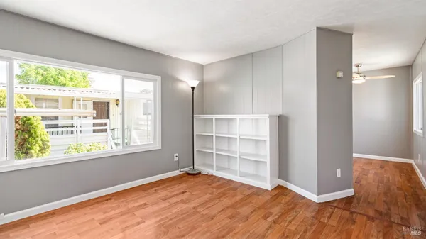a view of an empty room with wooden floor and a window