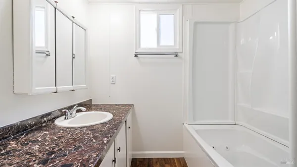 a bathroom with a granite countertop sink a mirror and a bathtub