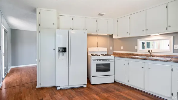a kitchen with granite countertop white cabinets and refrigerator
