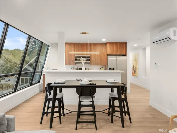 a kitchen with stainless steel appliances kitchen island a table chairs in it and wooden floors