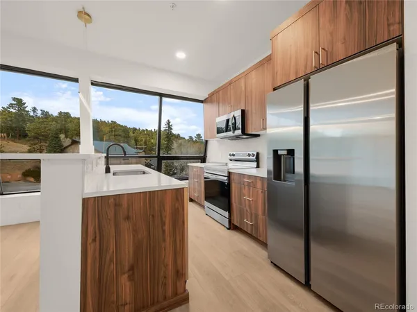 a kitchen with stainless steel appliances a refrigerator a sink and white cabinets
