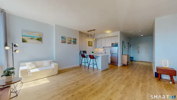 a living room with furniture and a dining table with kitchen appliances