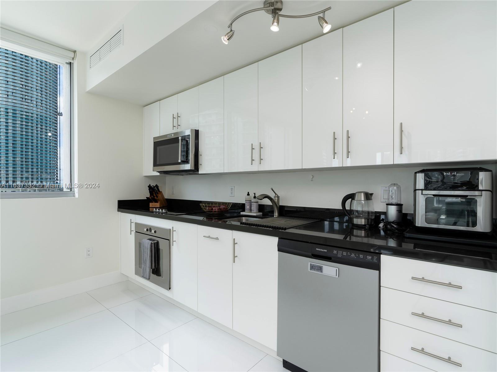 92 Southwest 3rd Street, Unit 1505 Miami, FL 33130 - Photo 14 of 37 a kitchen with granite countertop white cabinets and black appliances