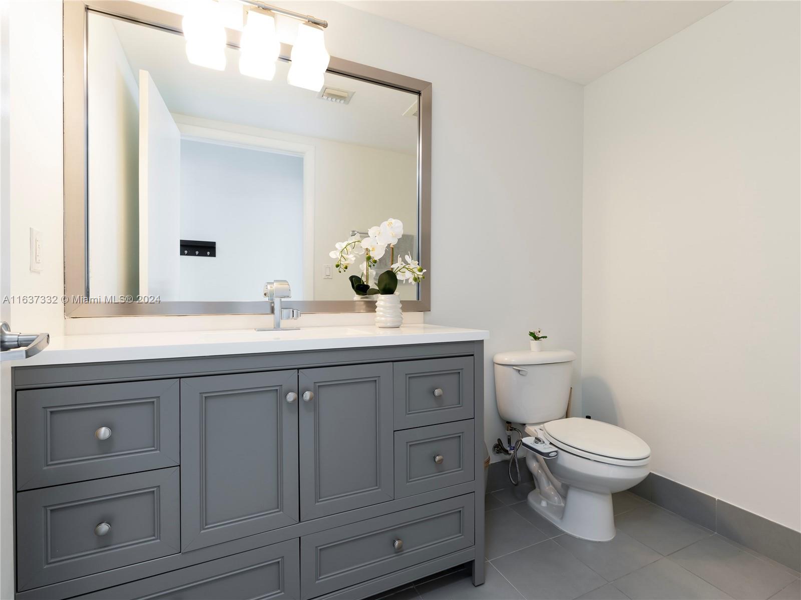 92 Southwest 3rd Street, Unit 1505 Miami, FL 33130 - Photo 15 of 37 a bathroom with a granite countertop toilet sink and mirror