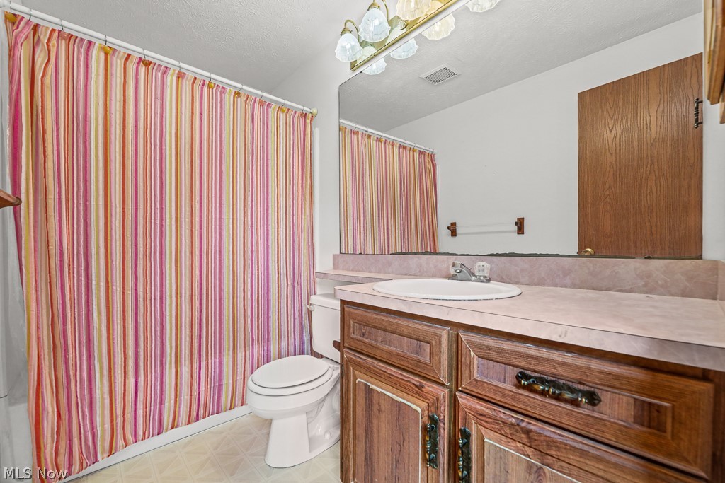 2642 Blake Road Wadsworth, OH 44281 - Photo 27 of 46 Full bathroom featuring a wood-finish vanity with a single basin sink, a large wall-mounted mirror, and a toilet