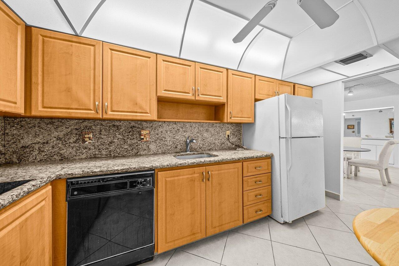 3460 South Ocean Boulevard, Unit 6150 Palm Beach, FL 33480 - Photo 11 of 34 a kitchen with stainless steel appliances granite countertop a refrigerator sink and cabinets