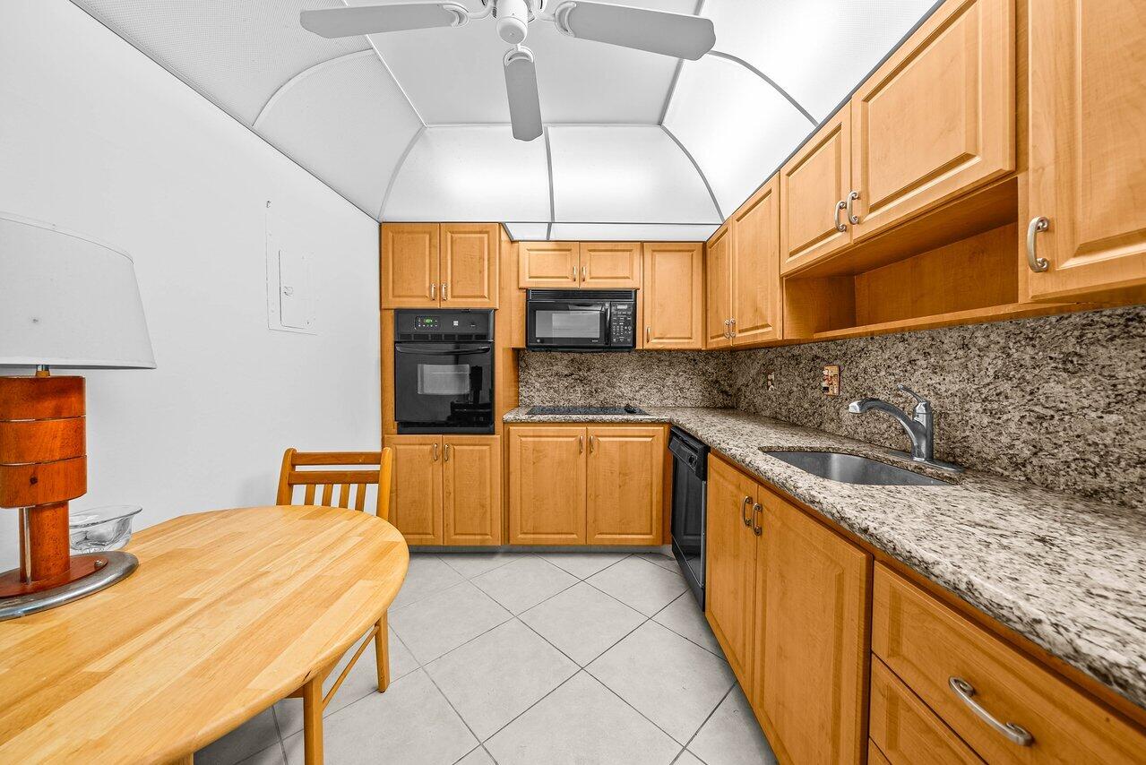 3460 South Ocean Boulevard, Unit 6150 Palm Beach, FL 33480 - Photo 10 of 34 a kitchen with stainless steel appliances granite countertop a sink a stove and a wooden cabinets