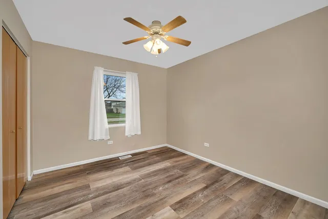 a view of an empty room with window and chandelier fan