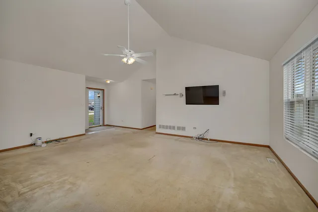 an empty room with windows and ceiling fan