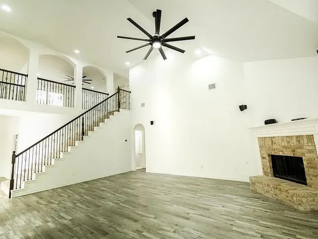 a view of an empty room with wooden floor and a fireplace