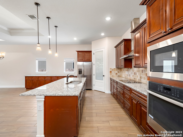 a large kitchen with stainless steel appliances kitchen island granite countertop a stove top oven a sink dishwasher a dining table and chairs with wooden floor