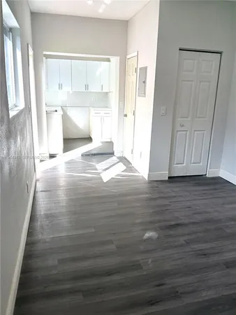 a view of kitchen and empty room with wooden floor