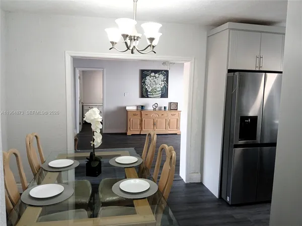 a dining room with wooden floor a chandelier a wooden table and chairs