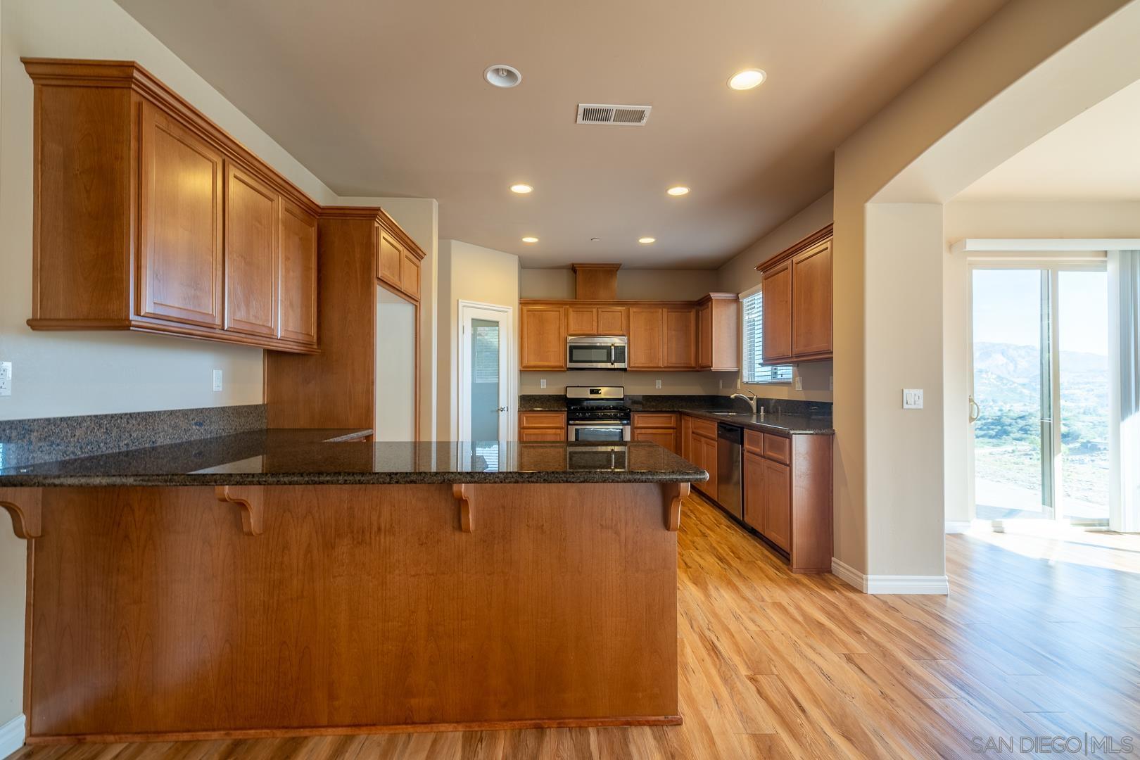 483 Alpine Trail Road Alpine, CA 91901 - Photo 17 of 42 a kitchen with stainless steel appliances granite countertop a refrigerator a stove top oven a sink and dishwasher with wooden floor